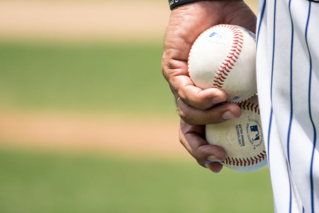 Close up hand holding two baseballs
