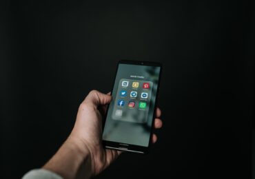 A person holding a phone with a folder full of social media