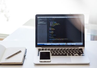 Laptop with coding on it with an iphone on top of it